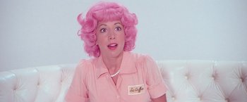Movie still from “Grease” (1978), directed by Randal Kleiser – A woman with pink hair and a pink shirt; Close Up shot, Over the shoulder angle