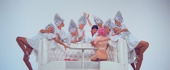 Movie still from “Grease” (1978), directed by Randal Kleiser – A group of people in silver hats and a woman in a pink dress; Wide shot, Overhead angle