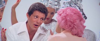 Movie still from “Grease” (1978), directed by Randal Kleiser – A man and two women in a mirror; Close Up shot, Over the shoulder angle