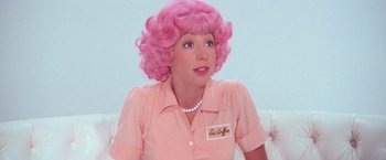 Movie still from “Grease” (1978), directed by Randal Kleiser – A person with pink hair and a pink shirt; Medium shot, Over the shoulder angle