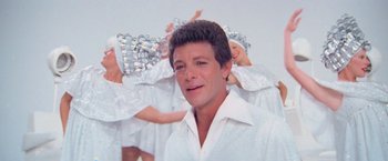 Movie still from “Grease” (1978), directed by Randal Kleiser – A person wearing a white shirt; Close Up shot, Low angle