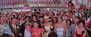 Movie still from “Grease” (1978), directed by Randal Kleiser – A group of people in a crowd at an event; Wide shot, High angle