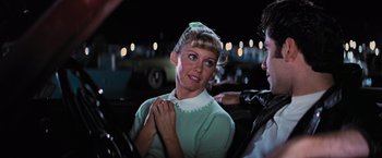 Movie still from “Grease” (1978), directed by Randal Kleiser – A woman in a green sweater and a man in a green shirt; Medium shot, Over the shoulder angle