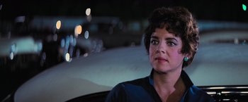 Movie still from “Grease” (1978), directed by Randal Kleiser – A woman sitting in the back seat of a car at night; Close Up shot, Over the shoulder angle