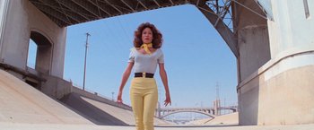Movie still from “Grease” (1978), directed by Randal Kleiser – A woman in yellow pants and a white shirt; Wide shot, Low angle
