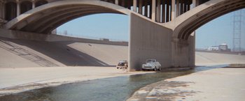 Movie still from “Grease” (1978), directed by Randal Kleiser – Two cars are parked on the side of a road; Extreme Wide shot, High angle