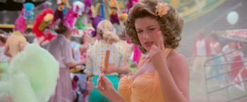 Movie still from “Grease” (1978), directed by Randal Kleiser – A woman in a yellow dress holding a popsicle in her hand; Close Up shot, Over the shoulder angle
