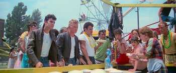 Movie still from “Grease” (1978), directed by Randal Kleiser – A group of men and women standing next to each other on a ferris wheel; Medium shot, Over the shoulder angle