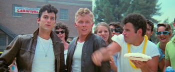 Movie still from “Grease” (1978), directed by Randal Kleiser – A group of young people standing around each other; Medium shot, Low angle