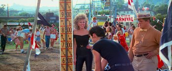 Movie still from “Grease” (1978), directed by Randal Kleiser – A woman standing next to a man on a ferris wheel; Medium shot, Over the shoulder angle