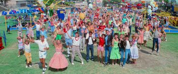 Movie still from “Grease” (1978), directed by Randal Kleiser – A group of people standing in the grass; Wide shot, High angle