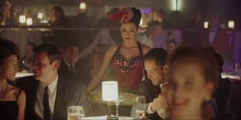 Movie still from “Green Book” (2018), directed by Peter Farrelly – A woman standing at a table in front of a candle; Medium shot, Over the shoulder angle