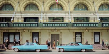 Movie still from “Green Book” (2018), directed by Peter Farrelly – A group of men standing next to a building with two cars parked in front of it; Extreme Wide shot, Low angle