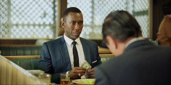Movie still from “Green Book” (2018), directed by Peter Farrelly – A man sitting at a table holding a dollar bill in front of another man; Close Up shot, Over the shoulder angle
