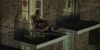 Movie still from “Green Book” (2018), directed by Peter Farrelly – A man sitting on a chair on a balcony reading; Extreme Wide shot, Low angle