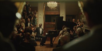 Movie still from “Green Book” (2018), directed by Peter Farrelly – A man sitting in front of a grand piano in front of an audience; Extreme Wide shot, High angle