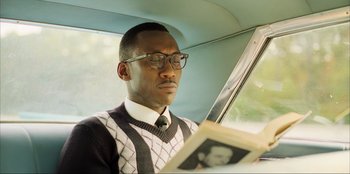 Movie still from “Green Book” (2018), directed by Peter Farrelly – A man sitting in the back of a car reading a newspaper; Close Up shot, Low angle