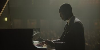 Movie still from “Green Book” (2018), directed by Peter Farrelly – A man sitting at a piano in front of an audience; Medium shot, Low angle