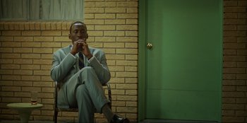 Movie still from “Green Book” (2018), directed by Peter Farrelly – A man sitting in a chair in front of a green door; Medium shot, Low angle