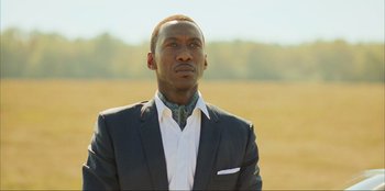 Movie still from “Green Book” (2018), directed by Peter Farrelly – A man wearing a suit and tie standing in a field; Close Up shot, Low angle