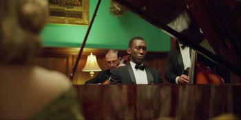 Movie still from “Green Book” (2018), directed by Peter Farrelly – A man sitting at a piano in front of two other men; Medium shot, Over the shoulder angle