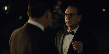 Movie still from “Green Book” (2018), directed by Peter Farrelly – A man smoking a cigarette while standing next to another man wearing a suit; Medium shot, Over the shoulder angle