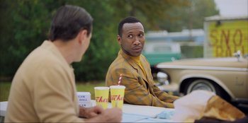 Movie still from “Green Book” (2018), directed by Peter Farrelly – Two men are sitting at a table with drinks in front of them; Medium shot, Over the shoulder angle