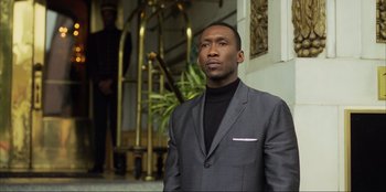 Movie still from “Green Book” (2018), directed by Peter Farrelly – A man wearing a suit and standing in front of a building; Medium shot, Low angle