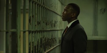 Movie still from “Green Book” (2018), directed by Peter Farrelly – A man in a suit and tie standing in front of a jail cell; Close Up shot, Low angle