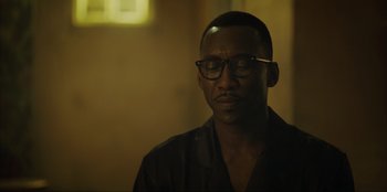 Movie still from “Green Book” (2018), directed by Peter Farrelly – A man with glasses sitting in a dark room; Close Up shot, Over the shoulder angle