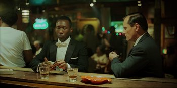 Movie still from “Green Book” (2018), directed by Peter Farrelly – Two men sitting at a bar looking at their cell phones; Medium shot, Over the shoulder angle
