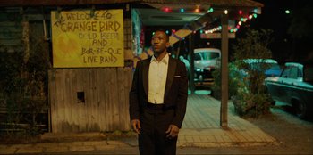 Movie still from “Green Book” (2018), directed by Peter Farrelly – A man in a suit standing in front of a sign; Medium shot, Over the shoulder angle