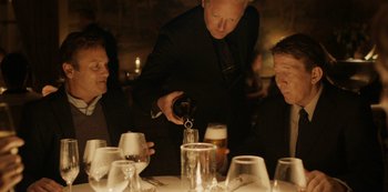 Movie still from “Another Round” (2020), directed by Thomas Vinterberg – A man pouring a glass of wine into a wine glass; Medium shot, Over the shoulder angle