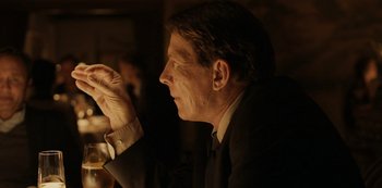 Movie still from “Another Round” (2020), directed by Thomas Vinterberg – A man sitting in a chair with a glass in his hand; Close Up shot, Over the shoulder angle