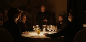Movie still from “Another Round” (2020), directed by Thomas Vinterberg – A group of people sitting at a table with wine glasses; Medium shot, Low angle