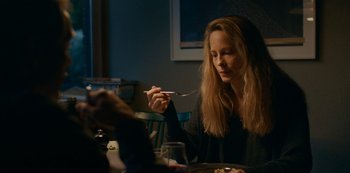 Movie still from “Another Round” (2020), directed by Thomas Vinterberg – A woman is eating at a table in a restaurant; Medium shot, Over the shoulder angle