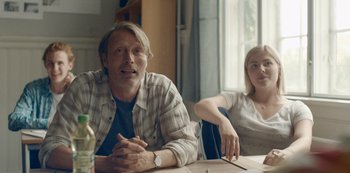 Movie still from “Another Round” (2020), directed by Thomas Vinterberg – A man and a woman sitting at a table in front of a window; Medium shot, Low angle