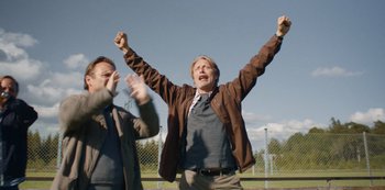 Movie still from “Another Round” (2020), directed by Thomas Vinterberg – A man with his hands in the air and another man with his hands in the air; Medium shot, Low angle