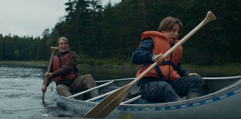 Movie still from “Another Round” (2020), directed by Thomas Vinterberg – A man and a boy paddling a canoe on a lake; Wide shot, Over the shoulder angle