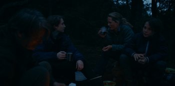 Movie still from “Another Round” (2020), directed by Thomas Vinterberg – Two people sitting on the ground at night drinking; Medium shot, Over the shoulder angle