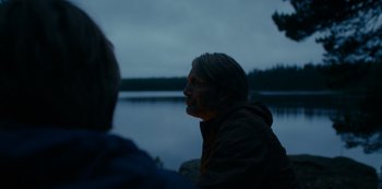 Movie still from “Another Round” (2020), directed by Thomas Vinterberg – A man sitting next to a body of water at night; Close Up shot, Over the shoulder angle
