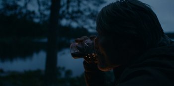 Movie still from “Another Round” (2020), directed by Thomas Vinterberg – A man drinking a glass of beer in the dark; Close Up shot, Over the shoulder angle
