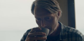 Movie still from “Another Round” (2020), directed by Thomas Vinterberg – A person drinking a cup of coffee; Close Up shot, Low angle