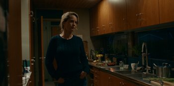 Movie still from “Another Round” (2020), directed by Thomas Vinterberg – A woman standing in a kitchen next to a sink; Medium shot, Over the shoulder angle