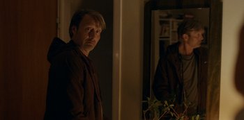 Movie still from “Another Round” (2020), directed by Thomas Vinterberg – A man standing in front of a mirror in a dark room; Medium shot, Over the shoulder angle