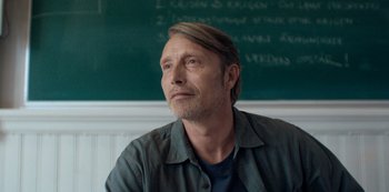 Movie still from “Another Round” (2020), directed by Thomas Vinterberg – A person sitting in front of a chalkboard; Close Up shot, Low angle