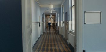 Movie still from “Another Round” (2020), directed by Thomas Vinterberg – A person walking down a long hallway in a building; Wide shot, High angle