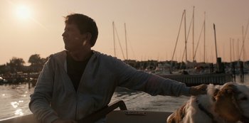 Movie still from “Another Round” (2020), directed by Thomas Vinterberg – A man sitting in a boat on a body of water; Medium shot, Over the shoulder angle