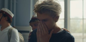 Movie still from “Another Round” (2020), directed by Thomas Vinterberg – A young man covering his face with his hands; Close Up shot, Over the shoulder angle