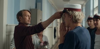 Movie still from “Another Round” (2020), directed by Thomas Vinterberg – A man is putting a hat on a woman's head; Close Up shot, Over the shoulder angle